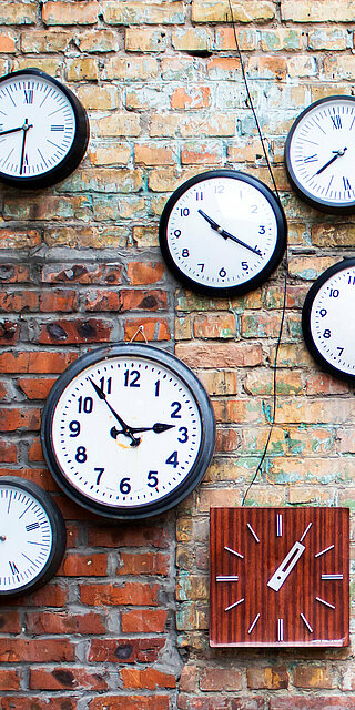 verschiedene Uhren, die an einer Wand hängen